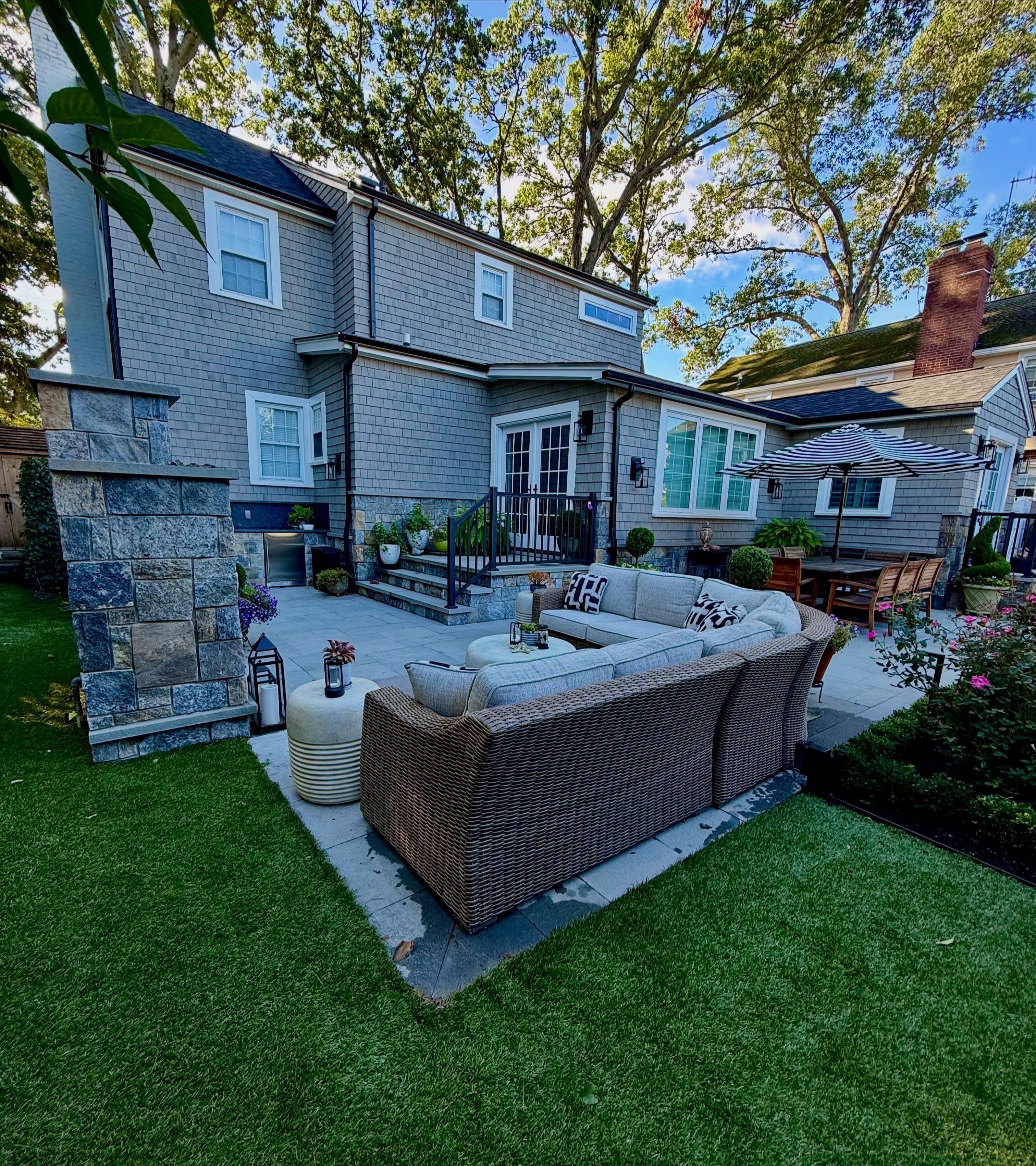 Bluestone terrace, stone fireplace, lawn behind a shingled house